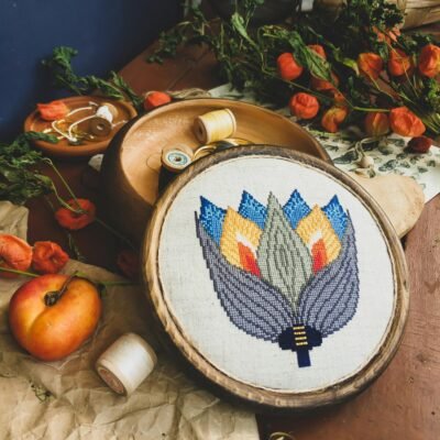 Beautiful handmade embroidery featuring a geometric flower design surrounded by dried flowers and fruit.